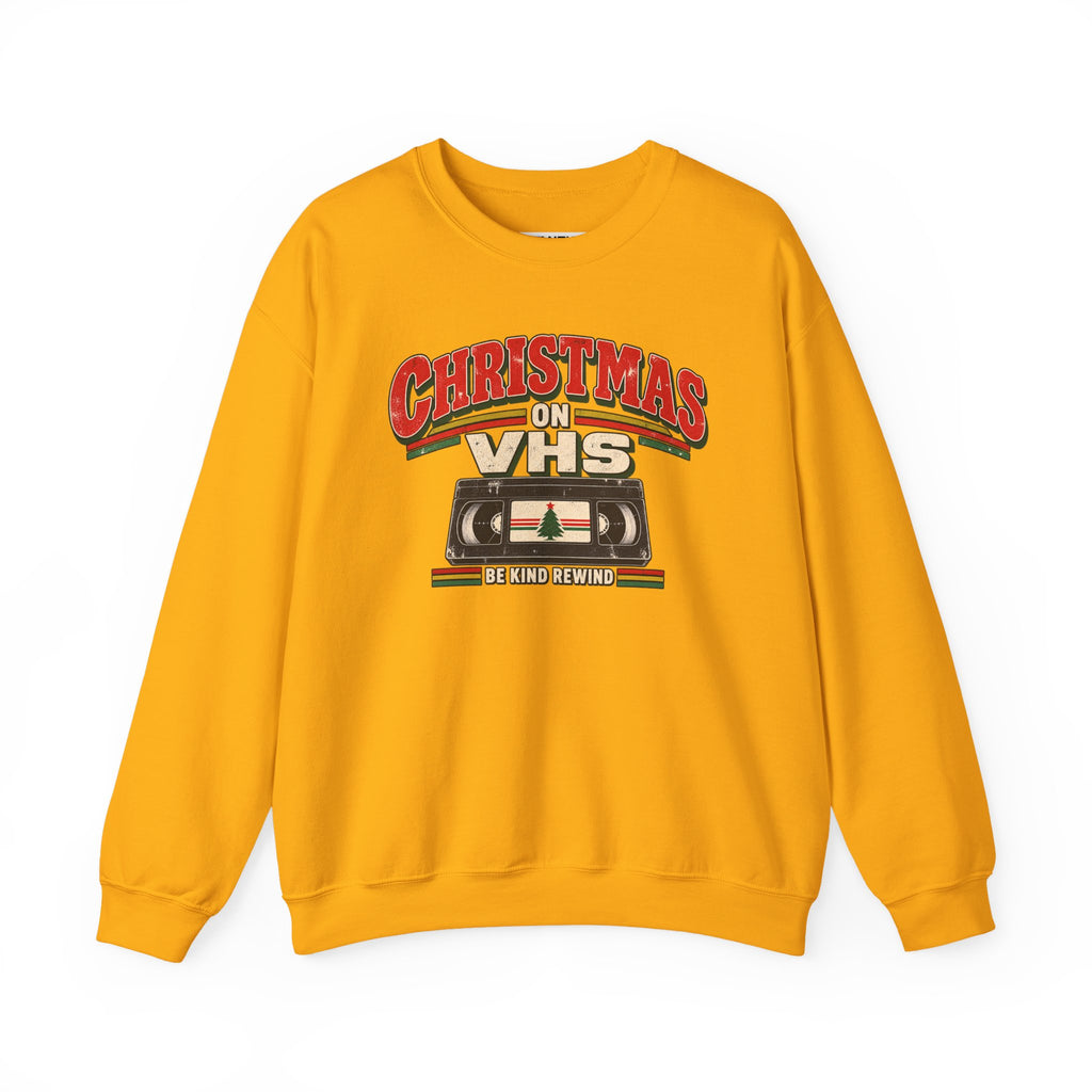 A yellow crewneck sweatshirt featuring a retro VHS graphic on the chest that reads 'CHRISTMAS ON VHS' with 'BE KIND REWIND' underneath, displayed on a clean white background.