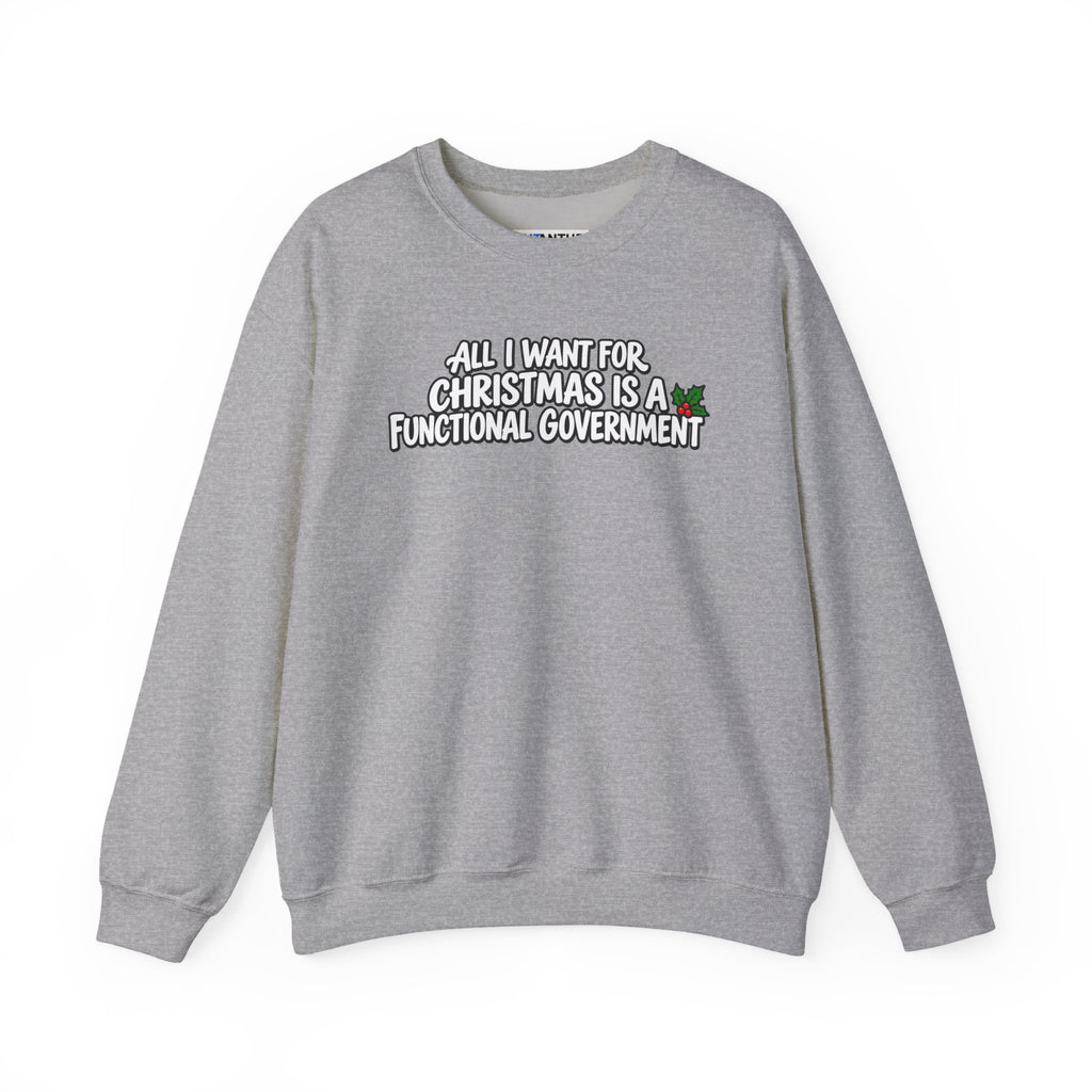 A gray crewneck sweatshirt with a graphic text print on the chest that reads 'ALL I WANT FOR CHRISTMAS IS A FUNCTIONAL GOVERNMENT' in white letters with a black outline, accompanied by a small green holly graphic.