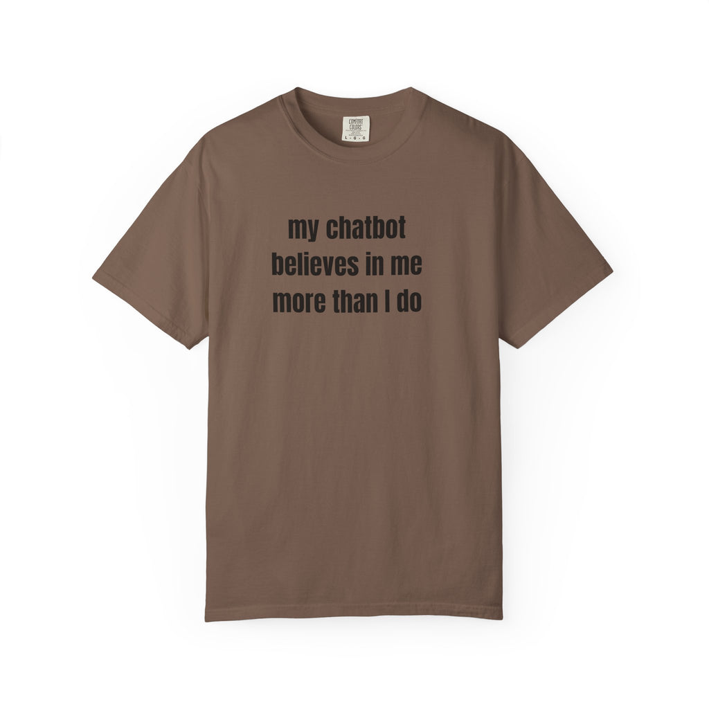 A brown short-sleeve crewneck t-shirt with the text 'my chatbot believes in me more than I do' printed in black sans-serif font on the chest, displayed against a solid white background.