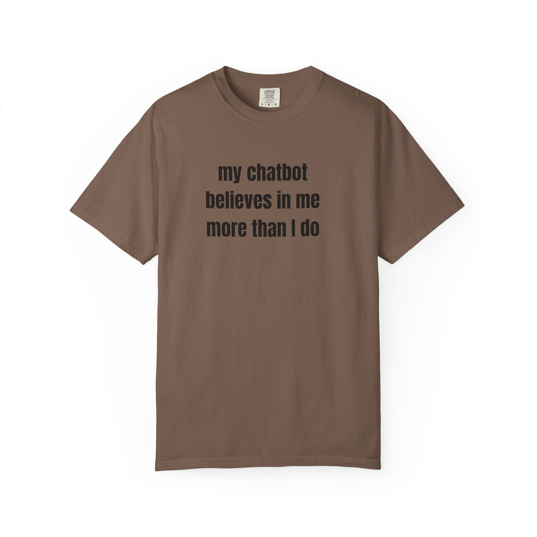 A brown short-sleeve crewneck t-shirt with the text 'my chatbot believes in me more than I do' printed in black sans-serif font on the chest, displayed against a solid white background.