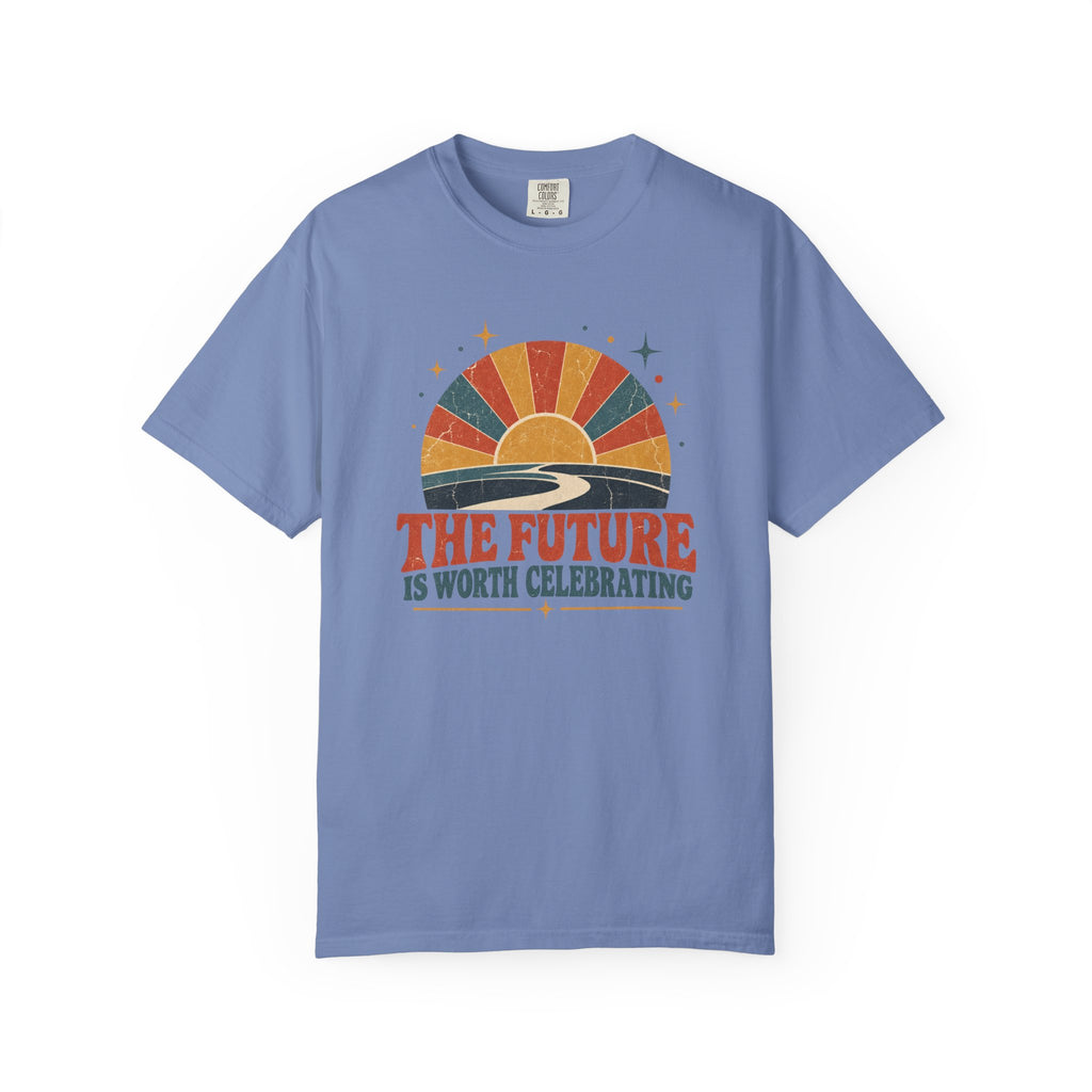 A light blue crewneck t-shirt with a retro sunset graphic and the text 'THE FUTURE IS WORTH CELEBRATING' printed on the chest, displayed on a clean white background.