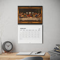 A spiral-bound wall calendar hanging on a light gray wall above a wooden desk. The top page shows a framed parody of the Last Supper with the diners playing Dungeons and Dragons, above the February 2027 calendar grid.