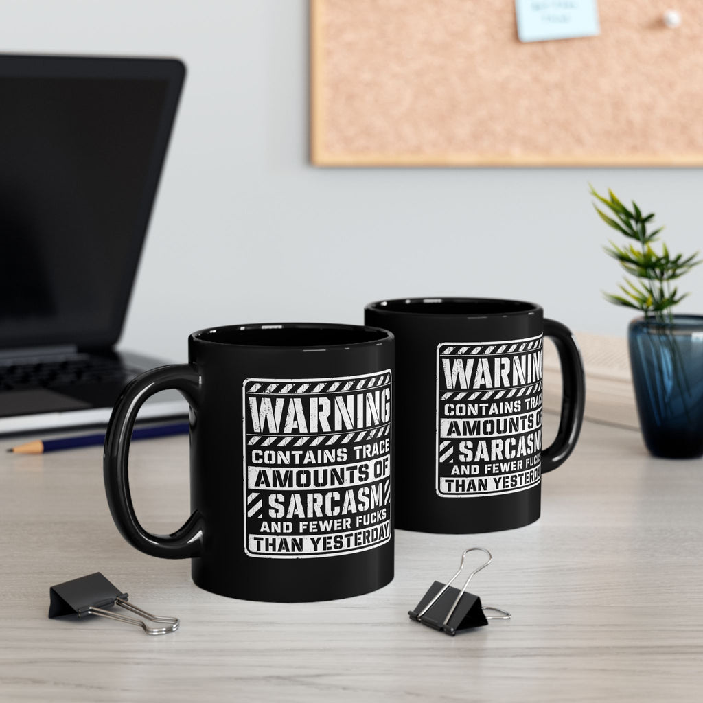 Black ceramic coffee mug printed with the warning label "Contains Trace Amounts of Sarcasm."