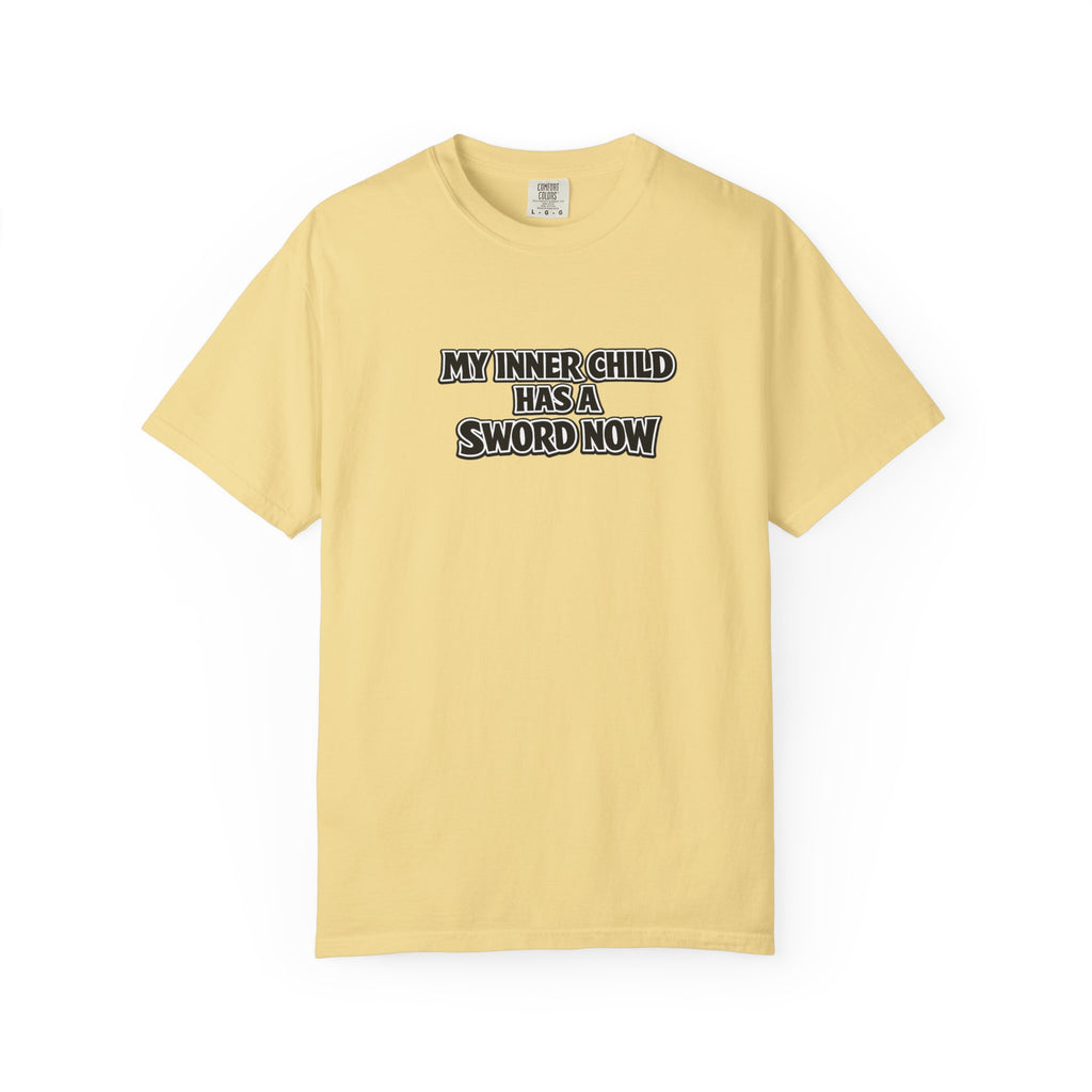 A pale yellow short-sleeve t-shirt with the text 'MY INNER CHILD HAS A SWORD NOW' printed in black and white block letters across the chest, displayed on a clean white background