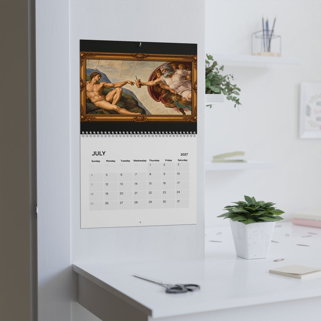 A spiral-bound wall calendar hanging on a white wall above a desk, featuring a classical painting of two figures reaching for light above the July 2027 calendar grid, in a bright modern home office with a small potted plant.