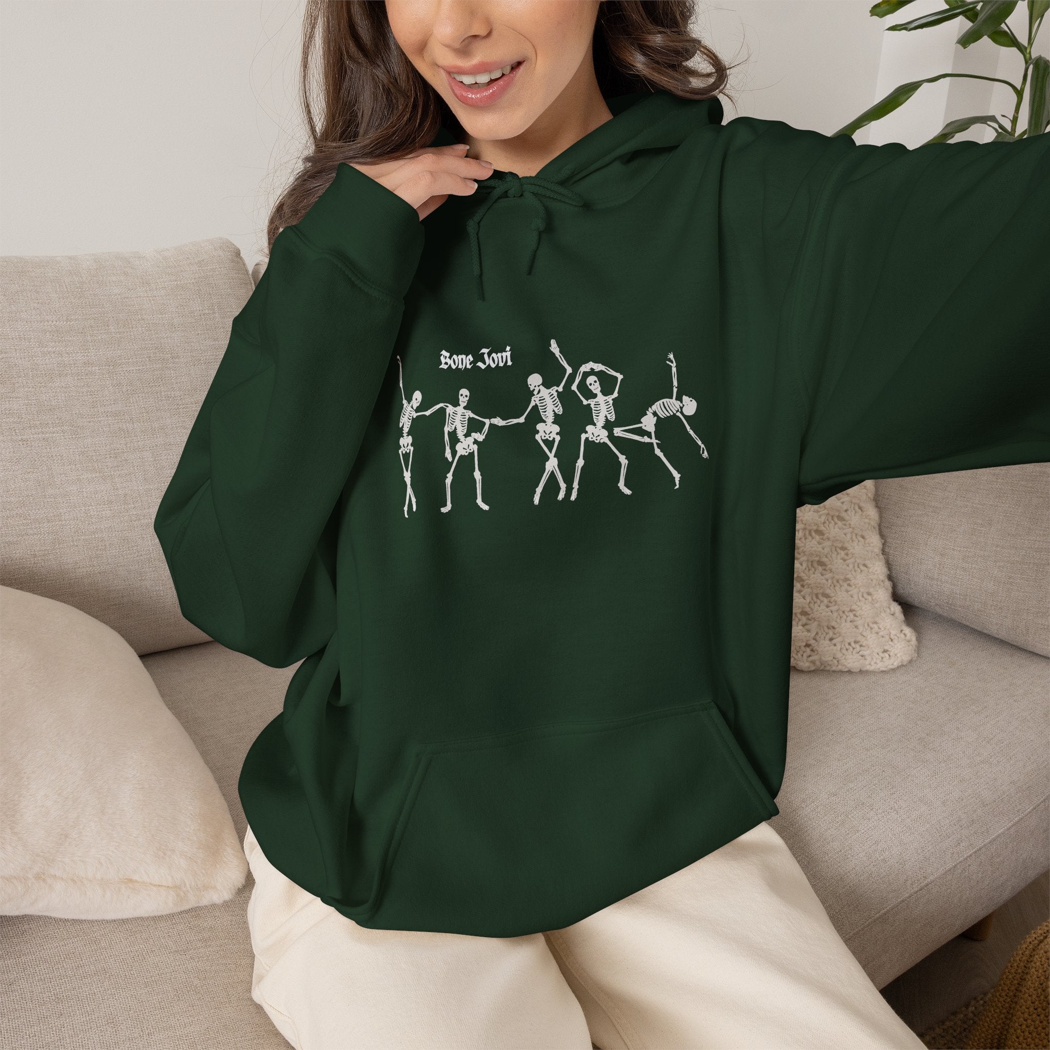 a women wearing a green  hoodie with 6 dancing white skeletons with the words Bone Jovi against a white background
