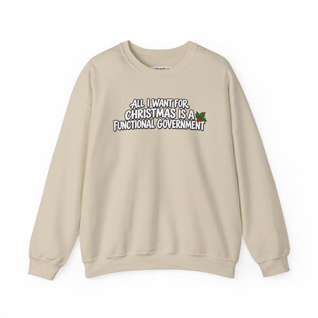 A light beige crewneck sweatshirt with a graphic text print on the chest that reads 'ALL I WANT FOR CHRISTMAS IS A FUNCTIONAL GOVERNMENT' in white letters with a black outline, accompanied by a small green holly graphic.