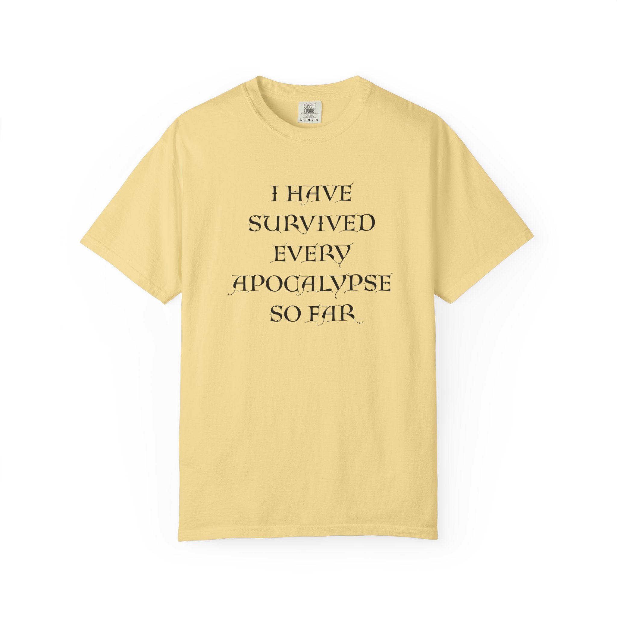 A pale yellow short-sleeve t-shirt with black text on the front reading 'I HAVE SURVIVED EVERY APOCALYPSE SO FAR.' on a plain white background.
