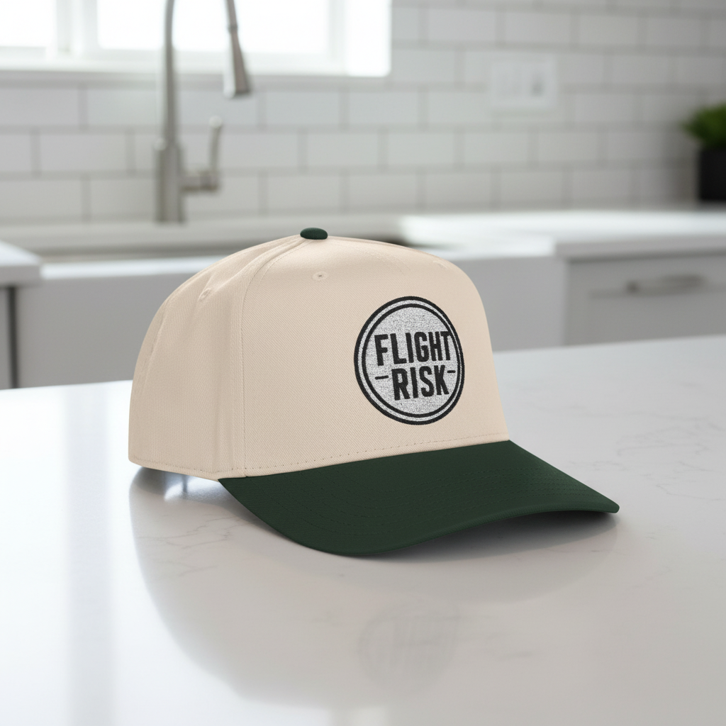Beige and green baseball cap with a logo  that says FLIGHT RISK on a white background
