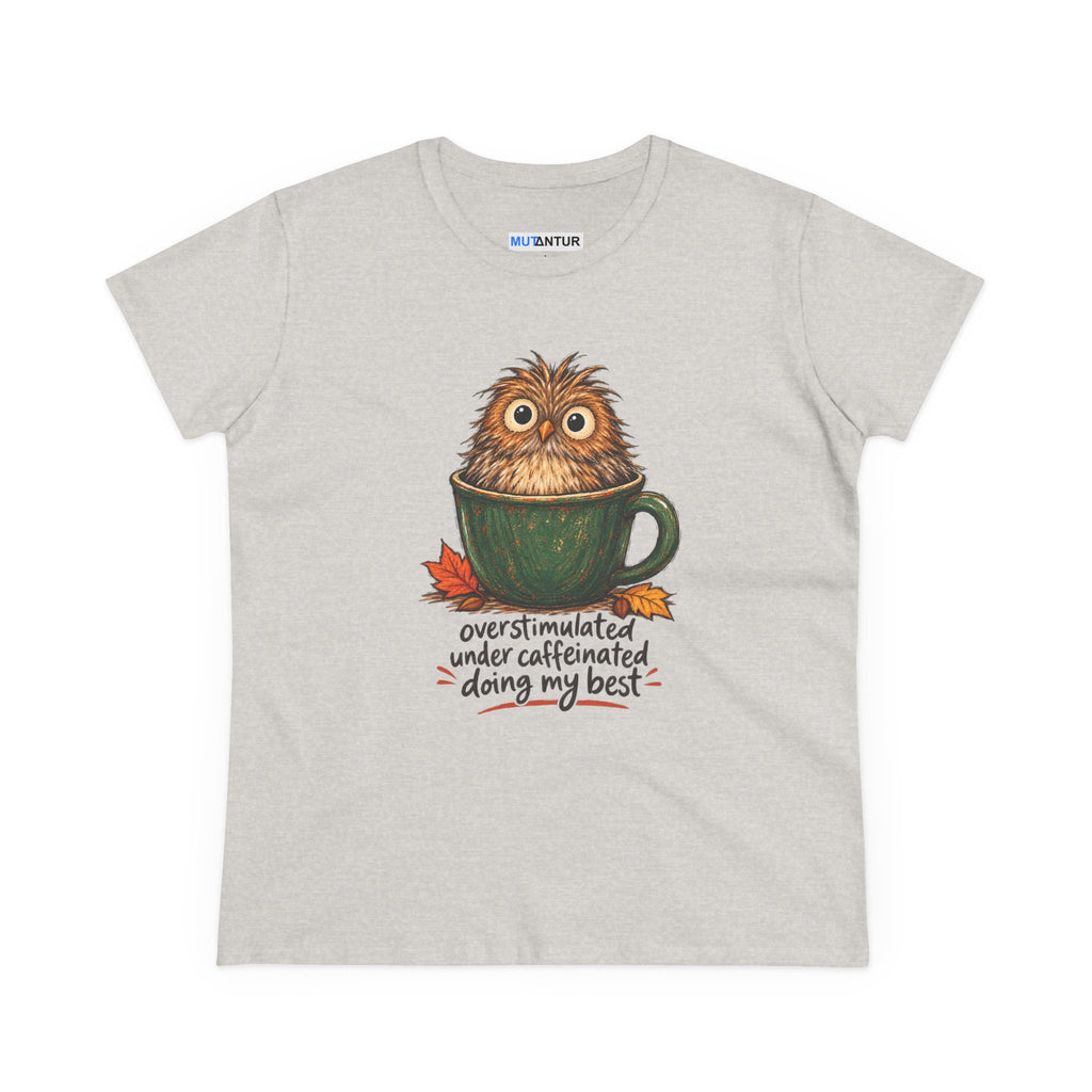 A light heather gray t-shirt featuring a cute graphic of a fluffy brown owl sitting inside a green coffee mug, with the text 'overstimulated under caffeinated doing my best' written below in a handwritten font. The shirt is displayed flat against a clean white background.