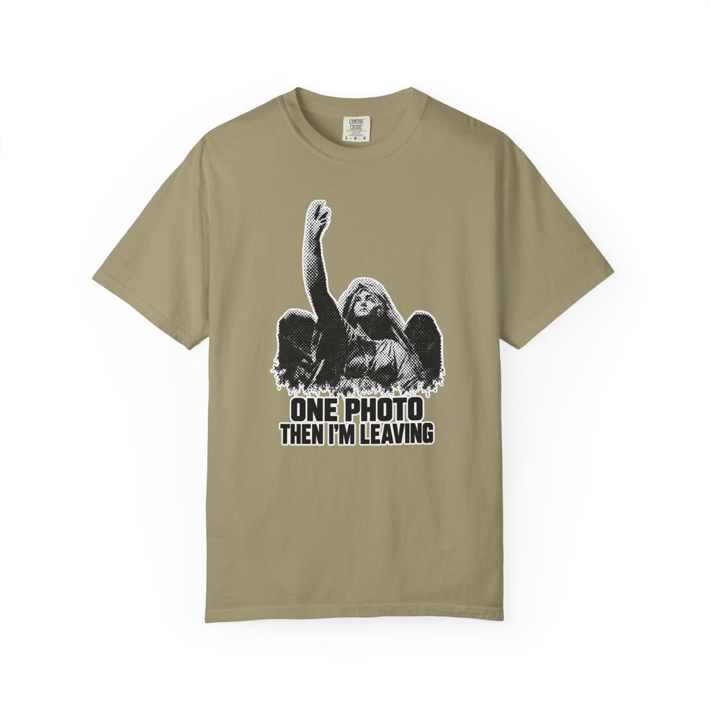 A khaki beige short-sleeve t-shirt with a black and white graphic of a winged angel figure raising its arm, above the text 'ONE PHOTO THEN I'M LEAVING'.