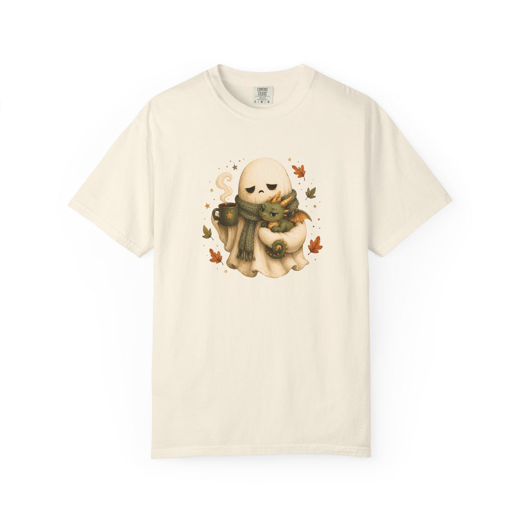 An off-white short-sleeve crewneck t-shirt featuring a central graphic of a cute, sleepy ghost wearing a green scarf and holding a mug, surrounded by small autumn leaves.
