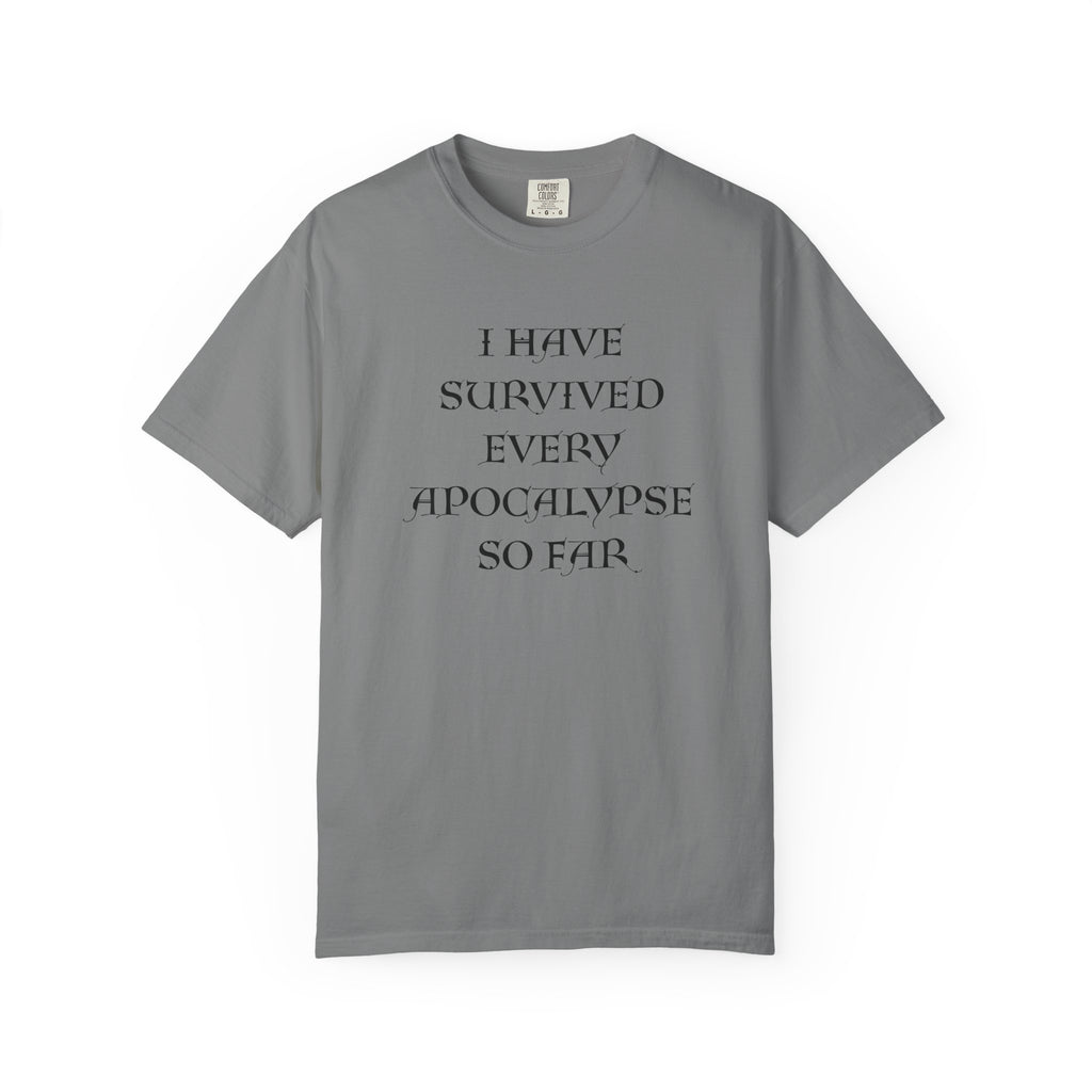 A grey short-sleeve t-shirt with black text on the front reading 'I HAVE SURVIVED EVERY APOCALYPSE SO FAR.' on a plain white background.