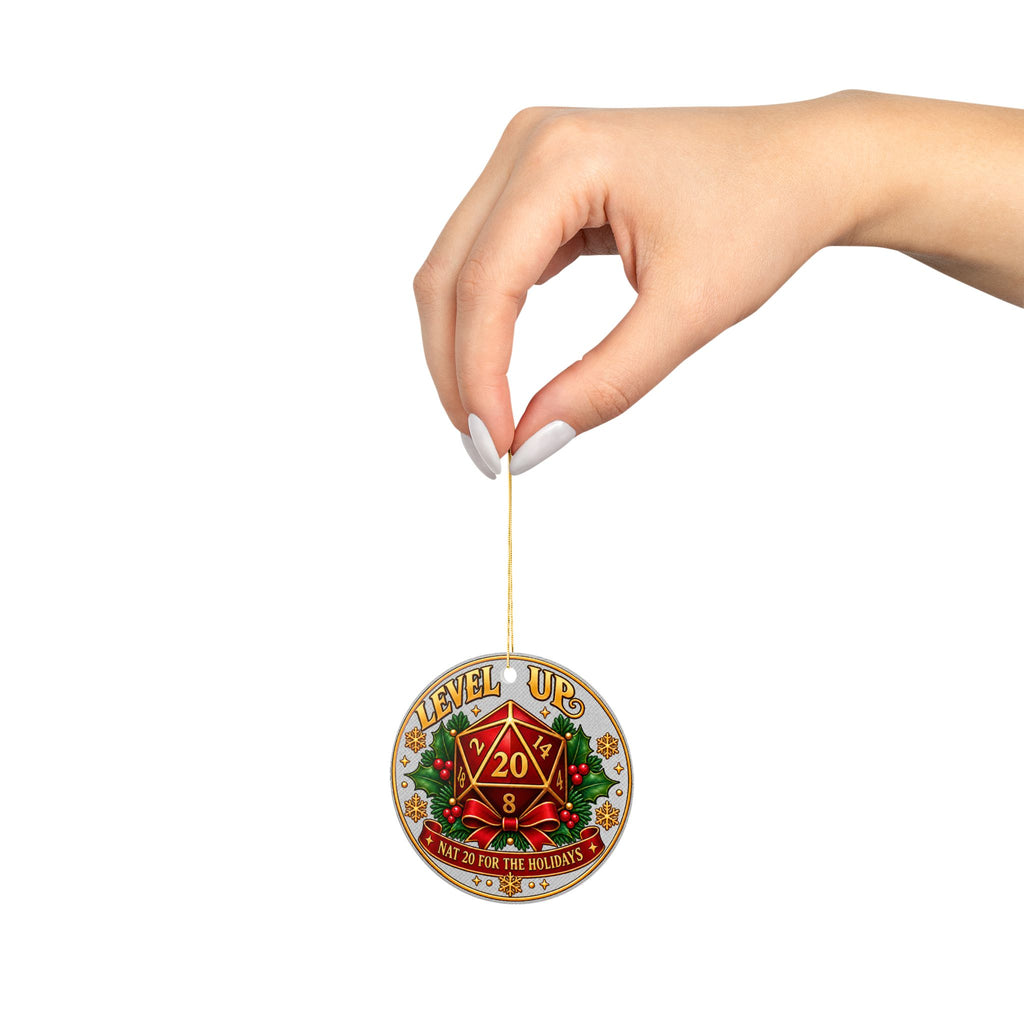 A hand with white manicured nails holds a small round enamel pin against a solid white background. The pin features a gold-toned border, a red multi-sided die with a '20' in the center, green pine branches, and the text 'LEVEL UP' and 'D20 IS THE NEW GOD DIE'.