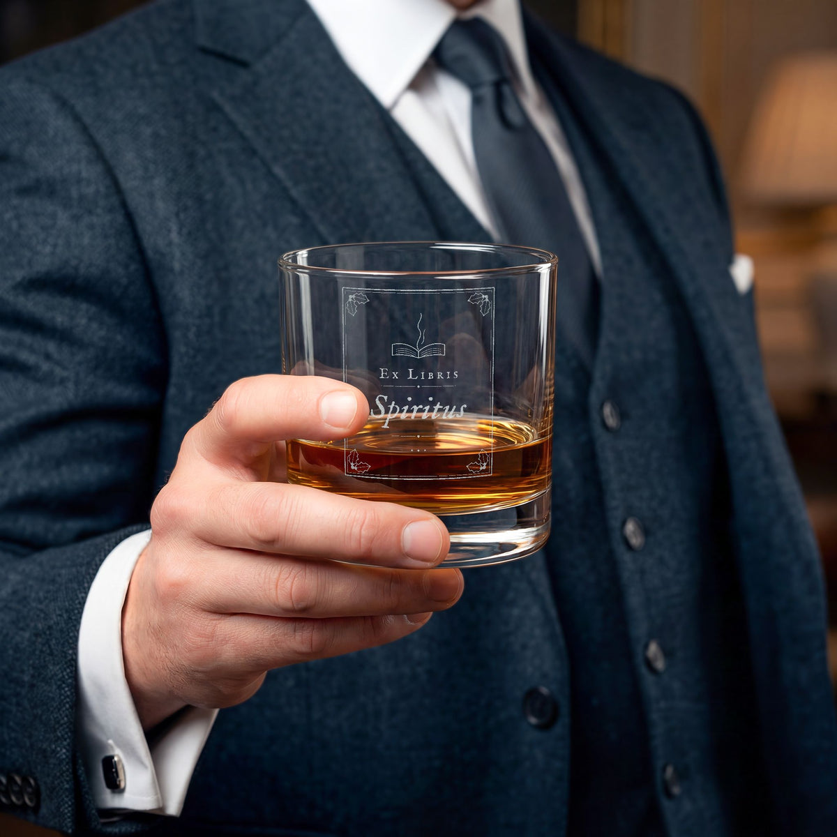 Man in a suit holding a glass of whiskey with a blurred background