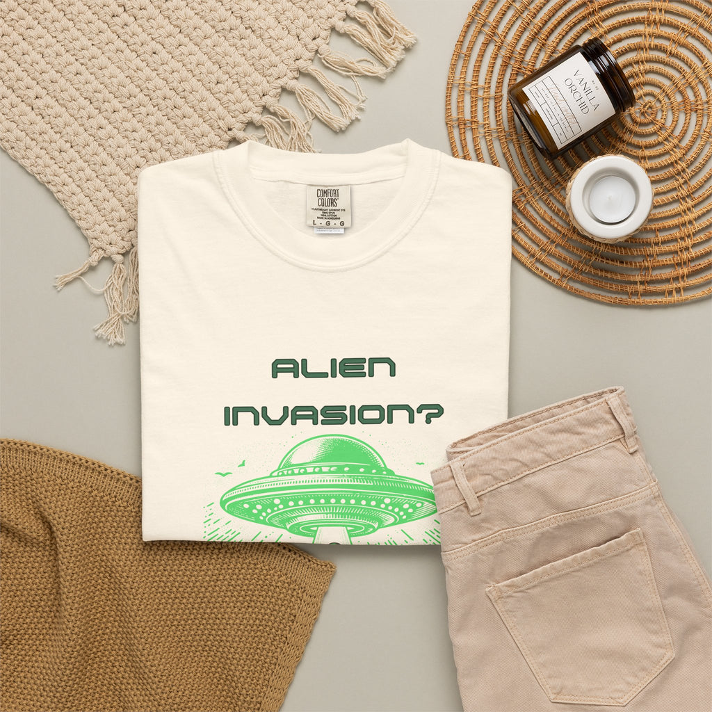 Alien Invasion Finally New Management UFO graphic tee in cream, folded flat lay styled with a knit throw, candle, and khaki pants