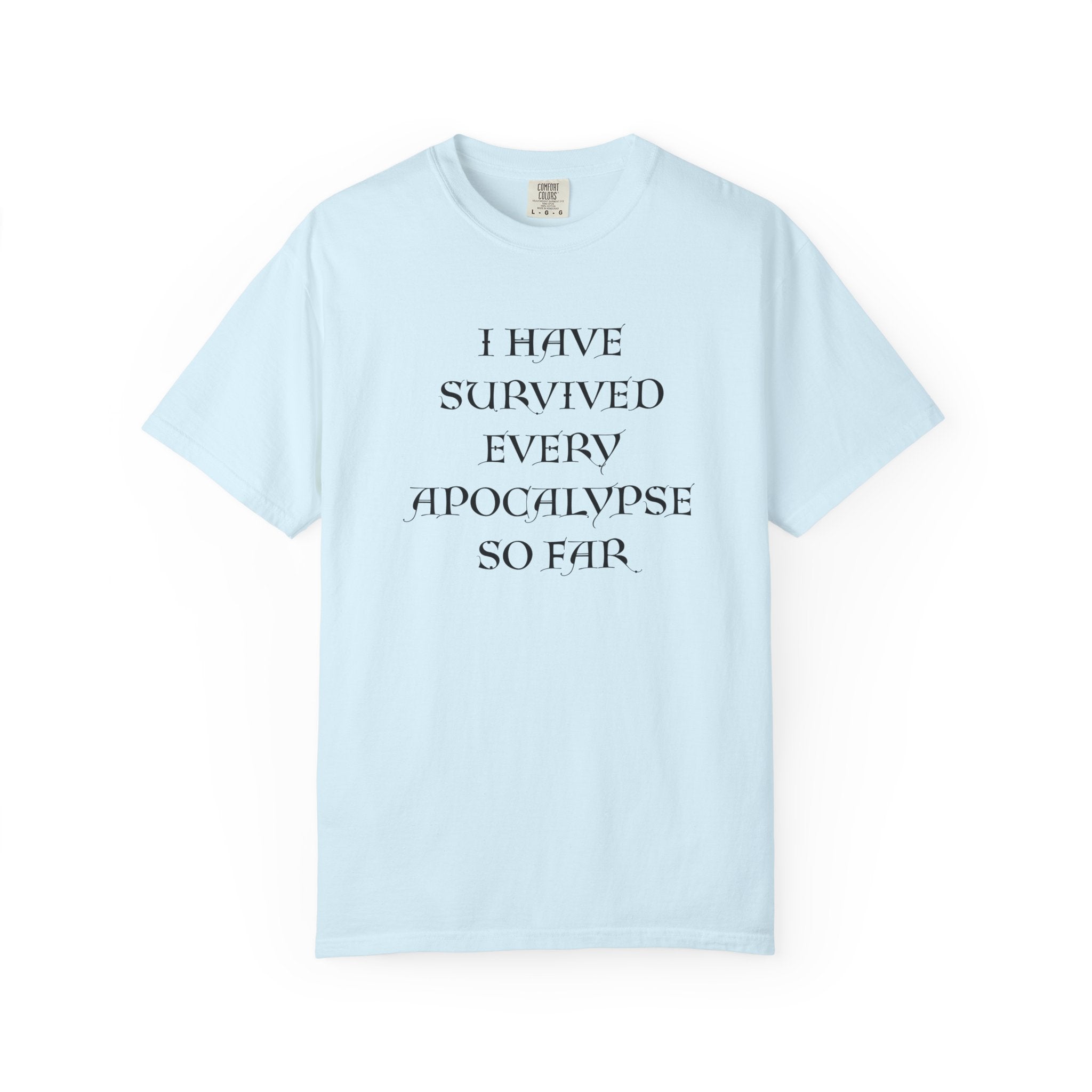 A light blue short-sleeve crewneck t-shirt with the text 'I HAVE SURVIVED EVERY APOCALYPSE SO FAR.' printed in black serif font on the chest, displayed against a solid white background.