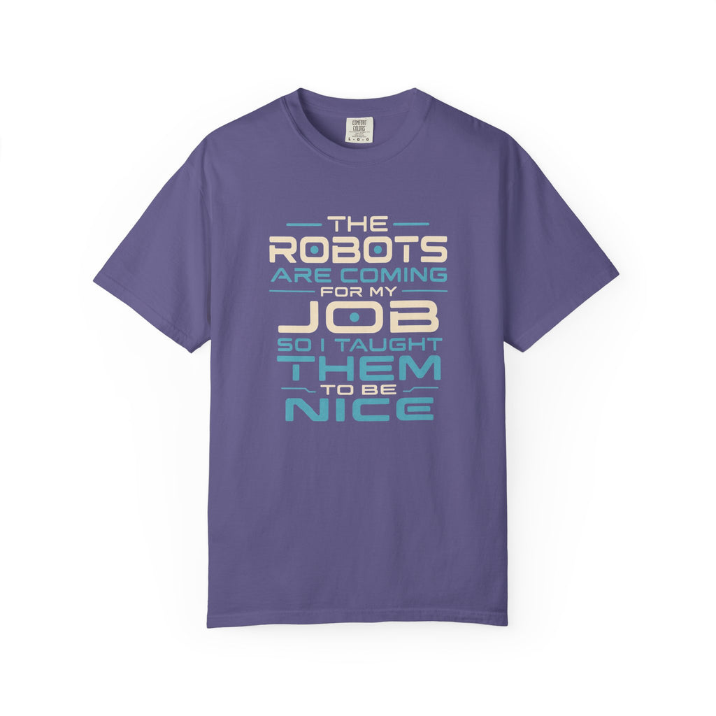 A purple short-sleeve crewneck t-shirt with a retro-style typographic graphic on the front that reads 'THE ROBOTS ARE COMING FOR MY JOB SO I TAUGHT THEM TO BE NICE' in cream, light blue, and dark blue lettering.