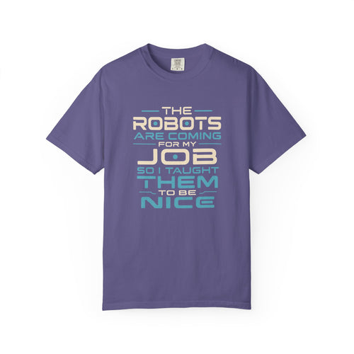 A purple short-sleeve crewneck t-shirt with a retro-style typographic graphic on the front that reads 'THE ROBOTS ARE COMING FOR MY JOB SO I TAUGHT THEM TO BE NICE' in cream, light blue, and dark blue lettering.