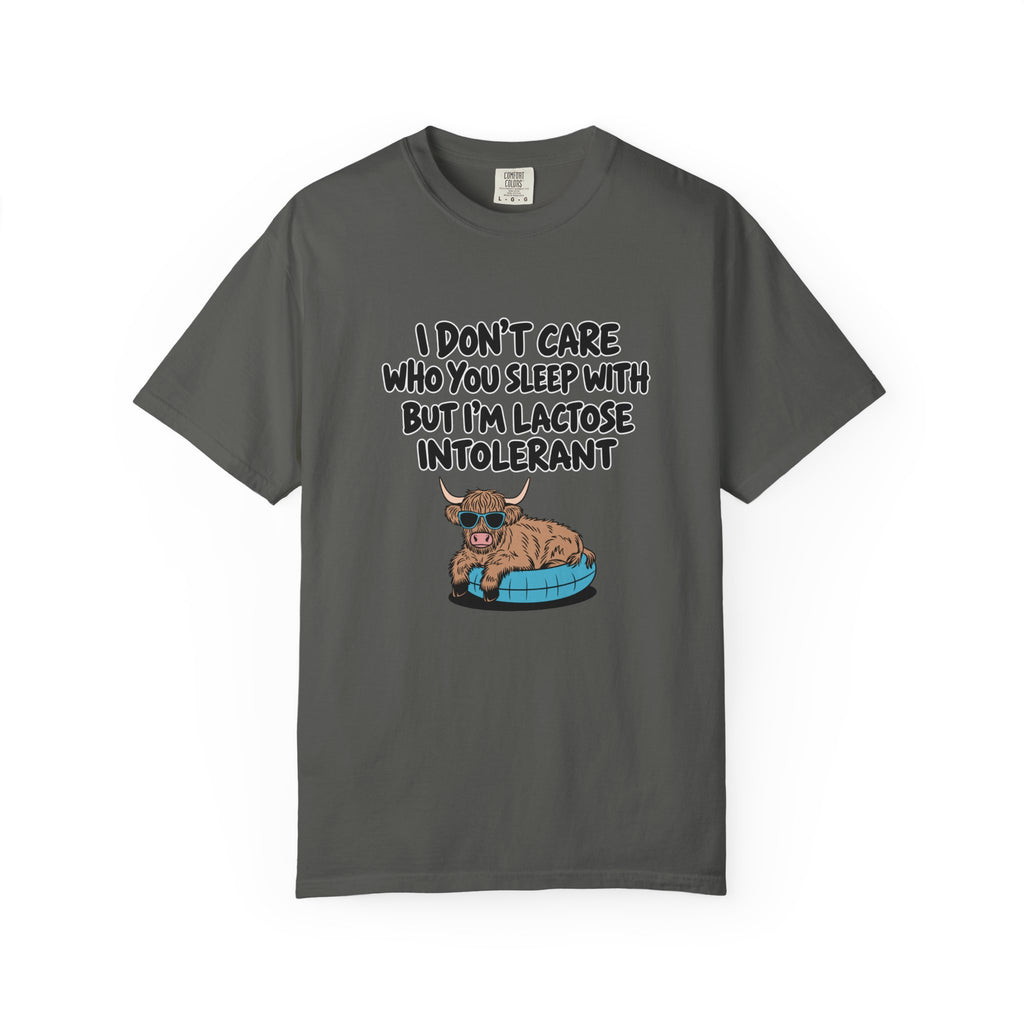 An grey short-sleeve t-shirt with a graphic print of a cartoon Highland cow sitting on a blue tire. The text above the cow reads, 'I DON'T CARE WHO YOU SLEEP WITH BUT I'M LACTOSE INTOLERANT' in a black hand-drawn font.