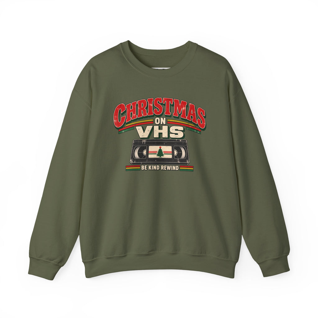 An olive green crewneck sweatshirt featuring a retro VHS graphic on the chest with the text 'CHRISTMAS ON VHS' and 'BE KIND REWIND' in red, beige, and green.

Details