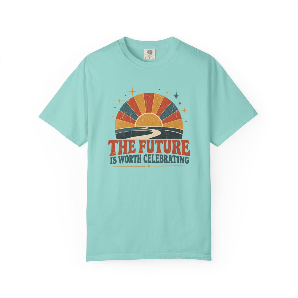 A light aqua blue short-sleeve t-shirt with a retro sunset graphic and the text 'THE FUTURE IS WORTH CELEBRATING' printed on the chest, displayed against a solid white background.