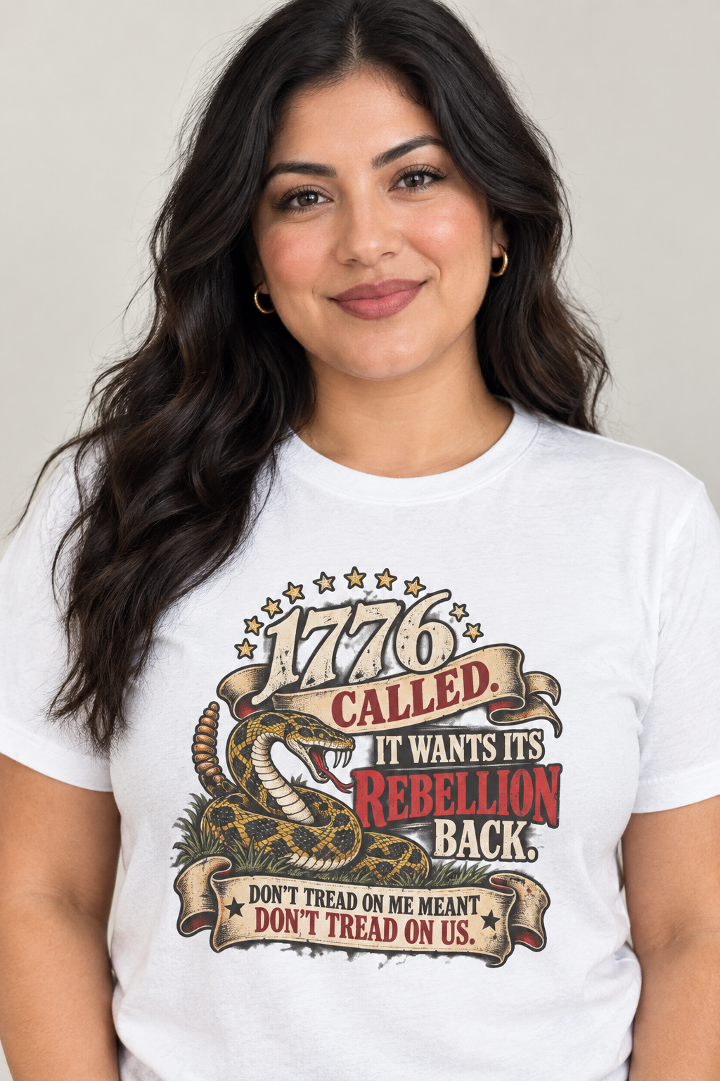 woman wearing a white t shirt with a colorful design of a coiled snake with the word s 1776 called It wants its rebellion back   then 'Dont read on me Meant don't tread on us' 
