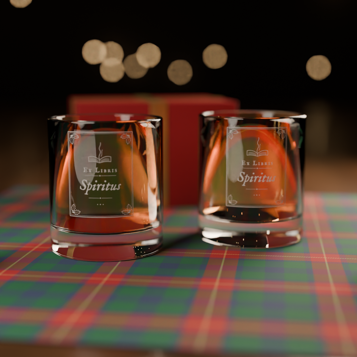 Two clear glass tumbler candles filled with amber liquid, each with a decorative label reading 'Ex Liberis Spiritus,' displayed on a red, green, and blue plaid surface with a blurred red box and warm bokeh lights in the background.