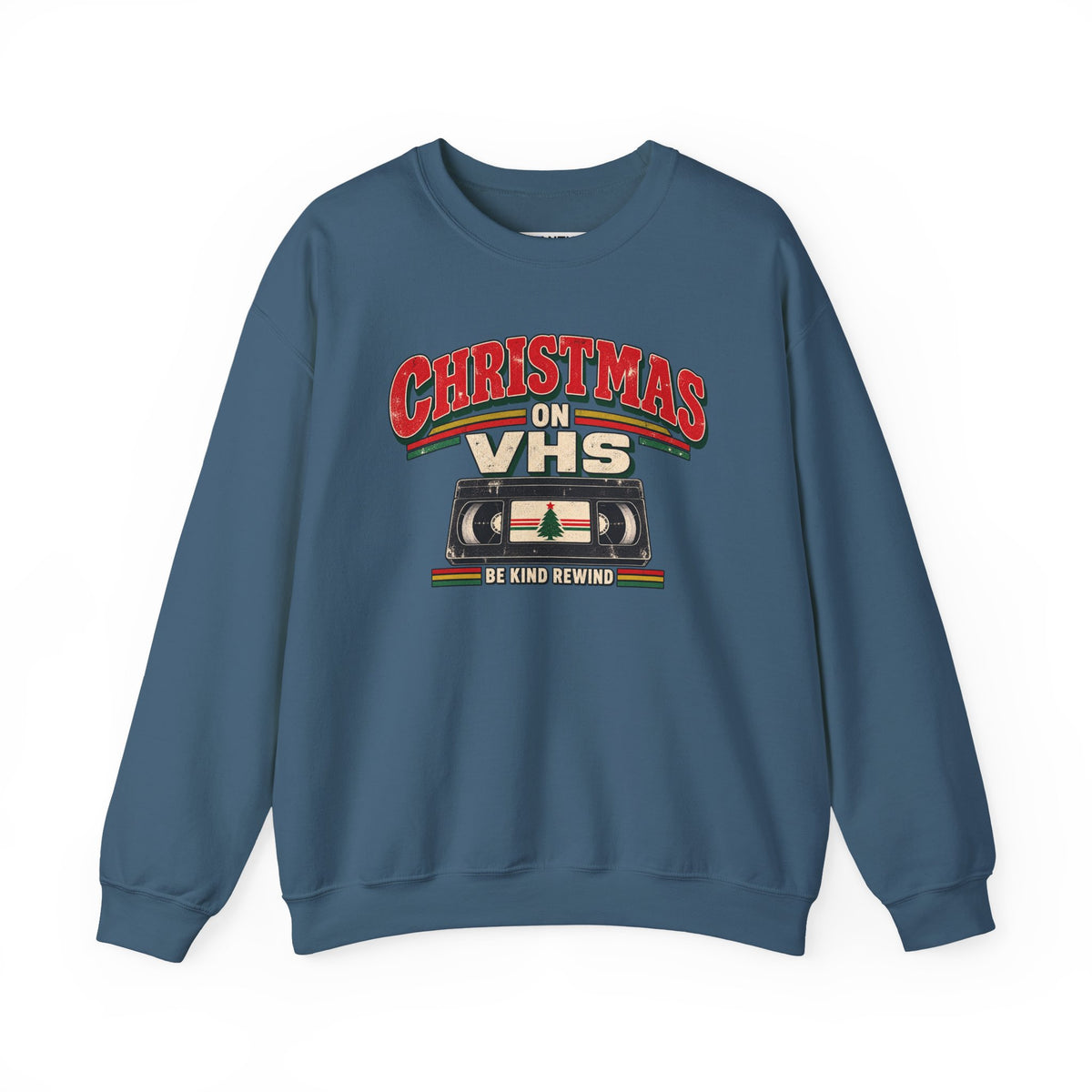 A slate blue crewneck sweatshirt featuring a retro Christmas graphic on the chest that reads 'CHRISTMAS ON VHS' in red and cream lettering above a cassette tape illustration, with 'BE KIND REWIND' underneath.