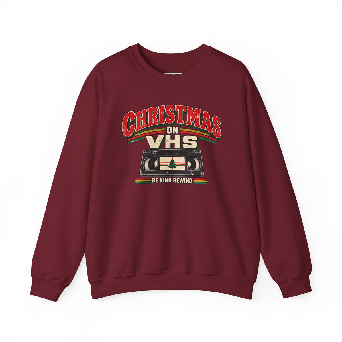 A maroon crewneck sweatshirt featuring a retro Christmas graphic on the chest that reads 'CHRISTMAS ON VHS' in red and cream lettering above a cassette tape illustration, with 'BE KIND REWIND' underneath.