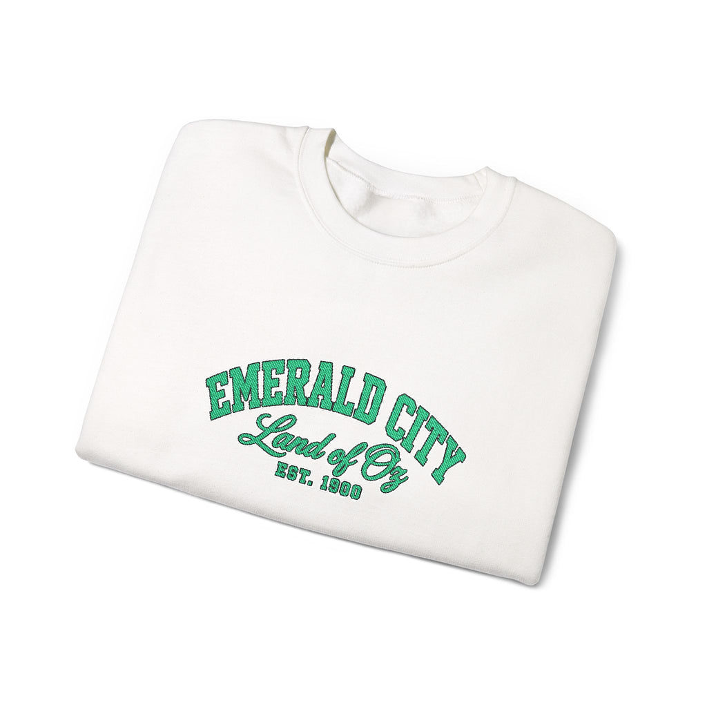 A folded white crewneck sweatshirt featuring 'EMERALD CITY Land of Oz EST. 1900' printed in green varsity-style lettering on the front, set against a plain white background.