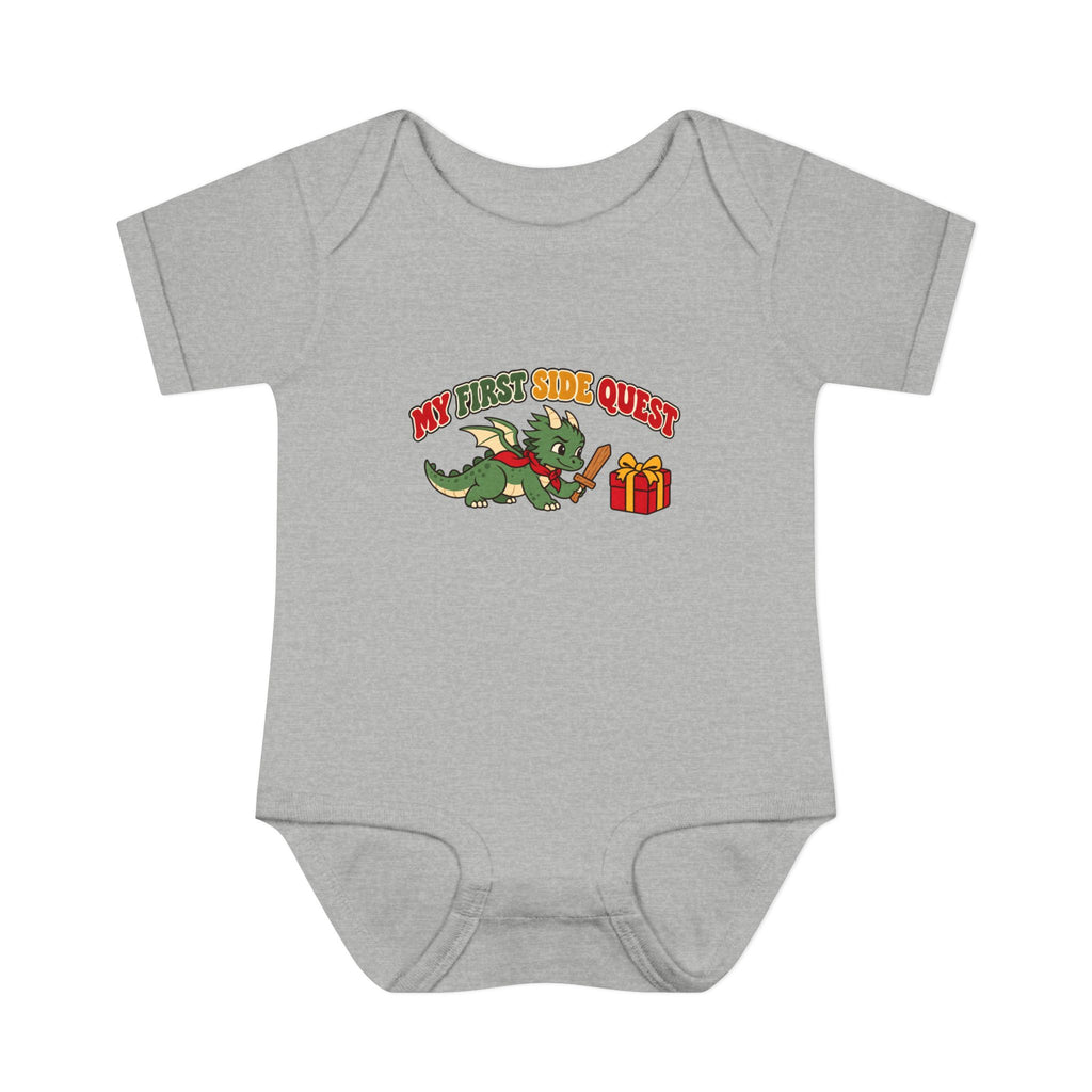 A light heather gray short-sleeve baby bodysuit featuring a cartoon graphic of a green dragon wearing a red wizard hat and holding a staff next to a red gift box, with the text 'MY FIRST SIDE QUEST' above it.