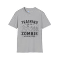 Grey short sleeved t shirt with the words Training for the zombie apocalypse with a funny line drawing of runners escaping zombies