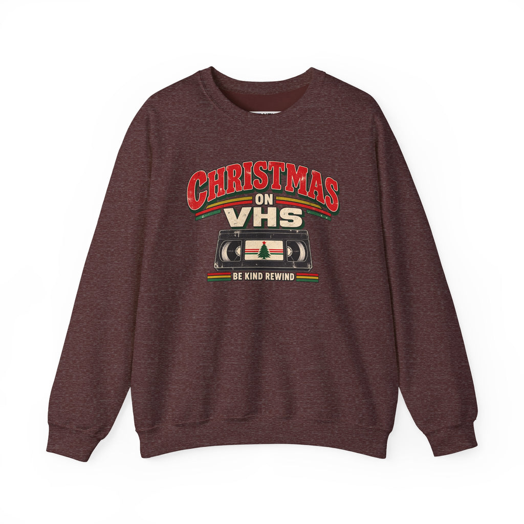 A dark heathered brown crewneck sweatshirt featuring a retro VHS graphic with the text 'CHRISTMAS ON VHS' and 'BE KIND REWIND' in red, beige, and green.
