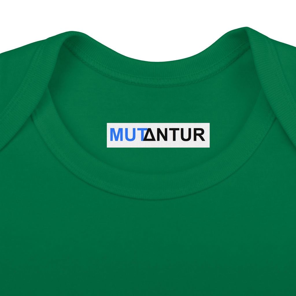 Close-up of a green crewneck t-shirt featuring a white rectangular label on the inner collar with the word 'MUTANTUR' printed in blue and black.