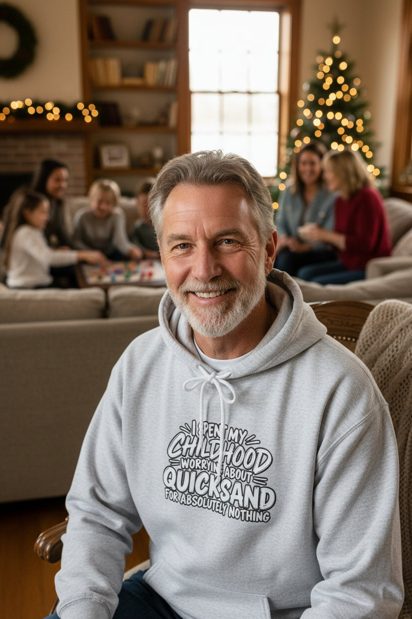 Man wearing a gray hoodie with white text that reads: I SPENT MY CHILDHOOD WORRYING ABOUT QUICKSAND FOR ABSOLUTELY NOTHING' against a white background