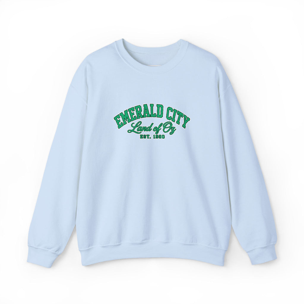 A light blue crewneck sweatshirt with 'EMERALD CITY Land of Oz EST. 1900' printed in green on the chest, displayed against a plain white background.