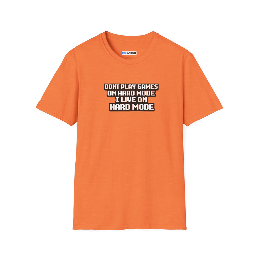 An orange short-sleeve crewneck t-shirt with a graphic text print on the chest that reads 'DONT PLAY GAMES ON HARD MODE I LIVE ON HARD MODE' in white letters with a black outline.