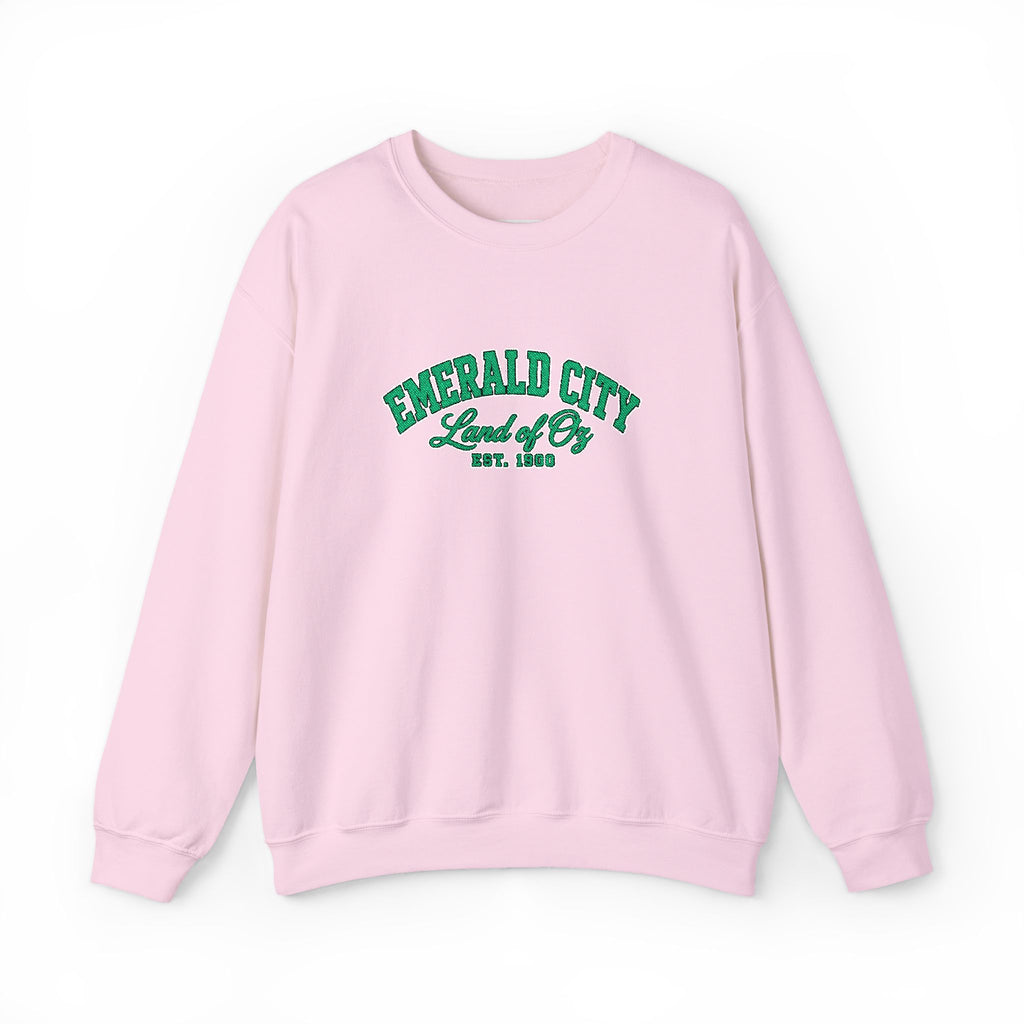 A light pink crewneck sweatshirt with 'EMERALD CITY Land of Oz EST. 1900' printed in green varsity-style lettering on the chest, displayed against a clean white background.