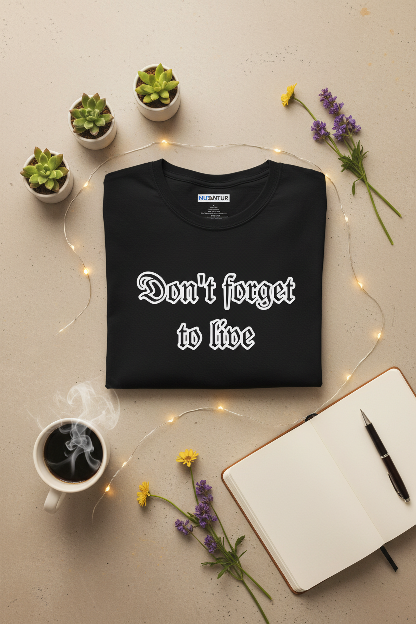 Black t-shirt with Gothic-script 'Don't Forget To Live' graphic, folded and styled with succulents, flowers, and coffee