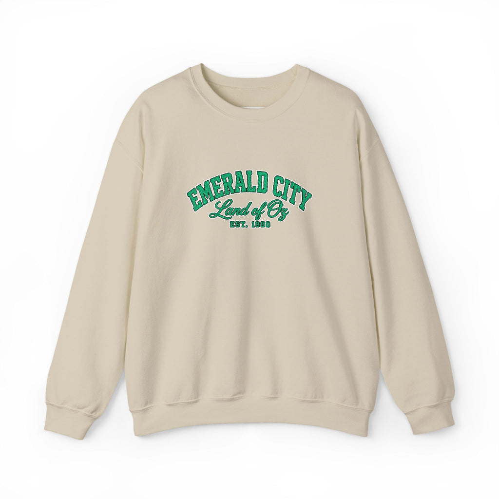 A beige crewneck sweatshirt with 'EMERALD CITY Land of Oz EST. 1900' printed in green on the chest, displayed against a plain white background.
