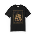 A black short-sleeve crewneck t-shirt featuring a large graphic print of the 'Strength' tarot card in a gold color on the front, displayed against a solid white background.