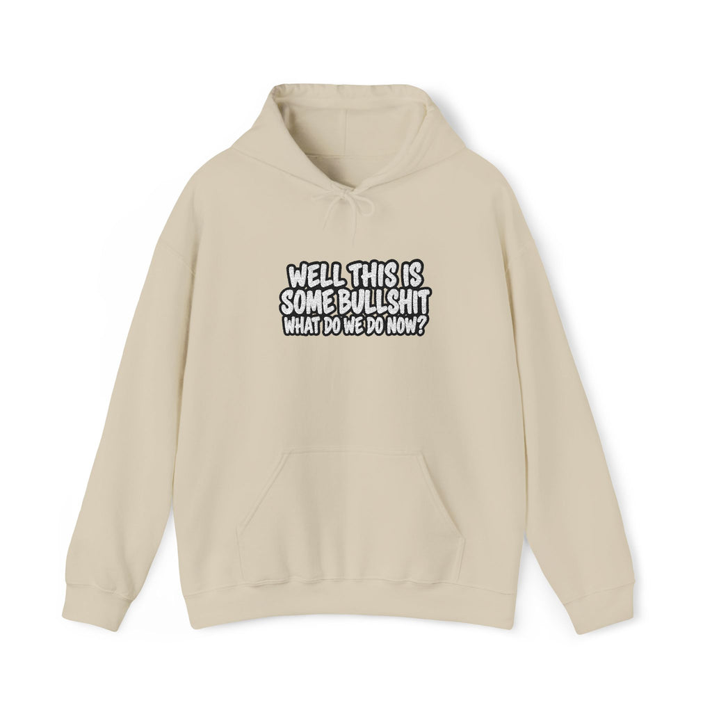 A beige hoodie with white text that says Well This is Some Bullshit What do we do Now? against a white background