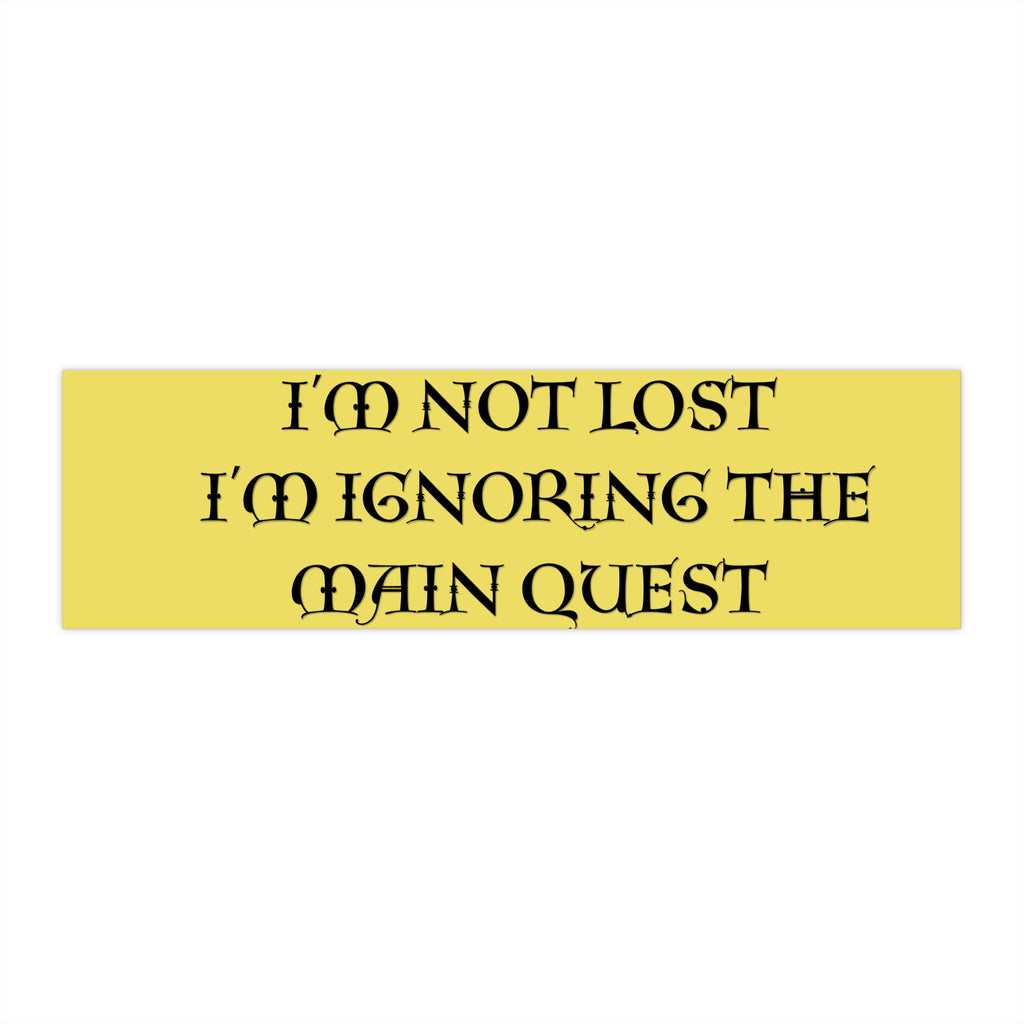 A rectangular yellow sign or sticker with black gothic-style text reading 'I'M NOT LOST I'M IGNORING THE MAIN QUEST' on a plain white background.