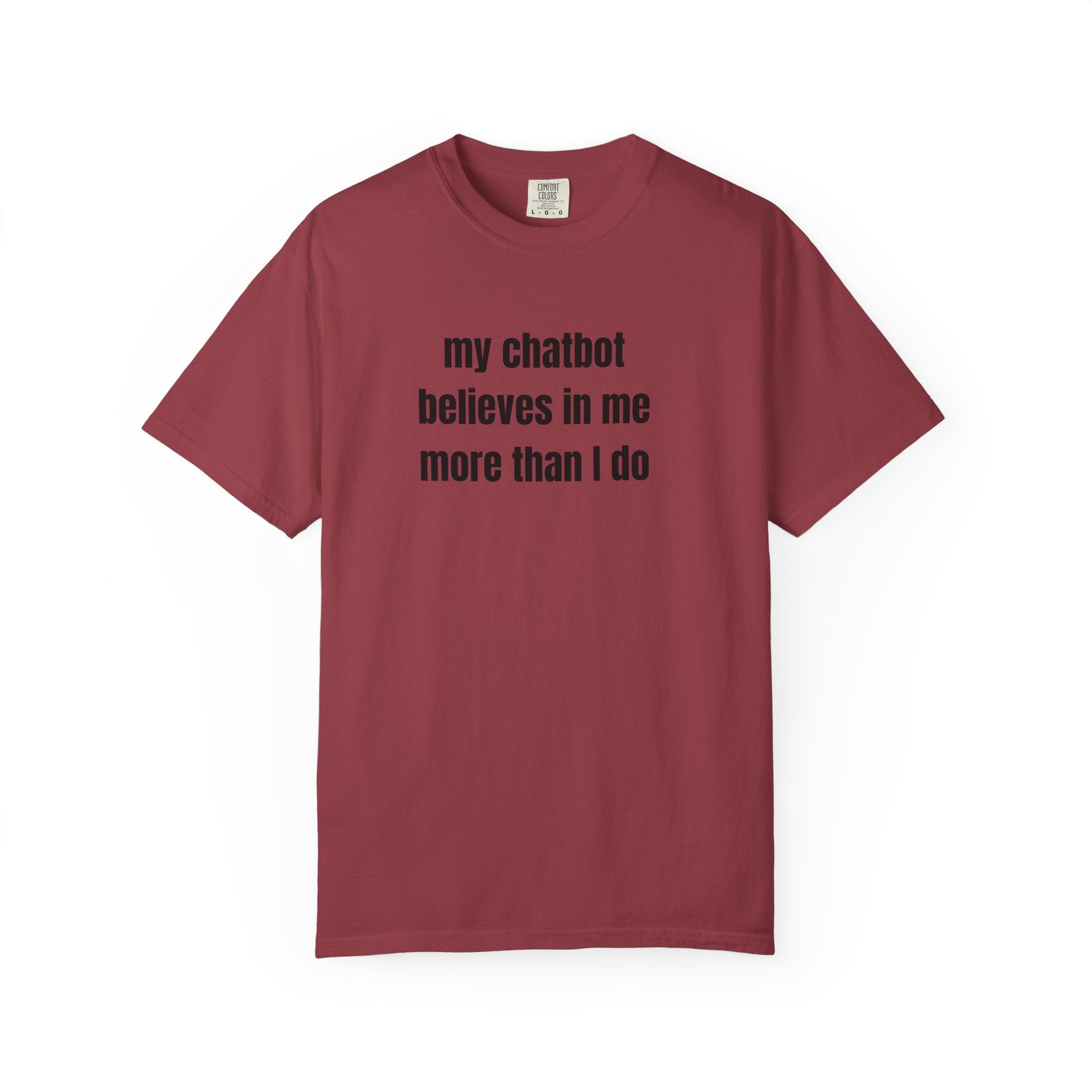 A maroon short-sleeve crewneck t-shirt with the text 'my chatbot believes in me more than I do' printed in black sans-serif font across the chest, displayed on a clean white background.