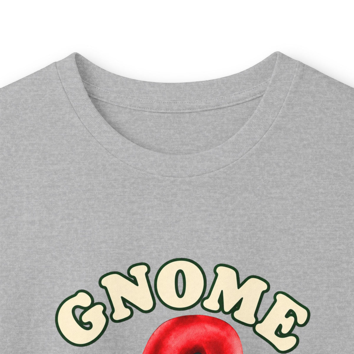Close-up of a heather gray t-shirt featuring a graphic print with the word 'GNOME' in cream-colored bubble letters with green outlines, above a red apple illustration.