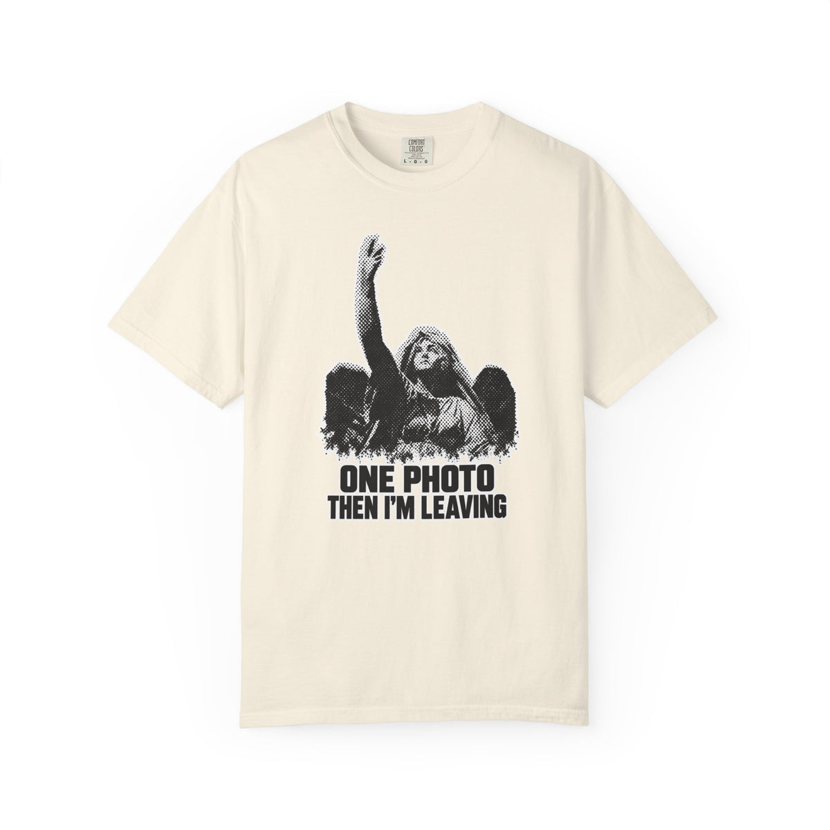 A beige  short-sleeve crewneck t-shirt in a  featuring a black and white graphic of an angel with one arm raised and the text 'ONE PHOTO THEN I'M LEAVING' printed below.
