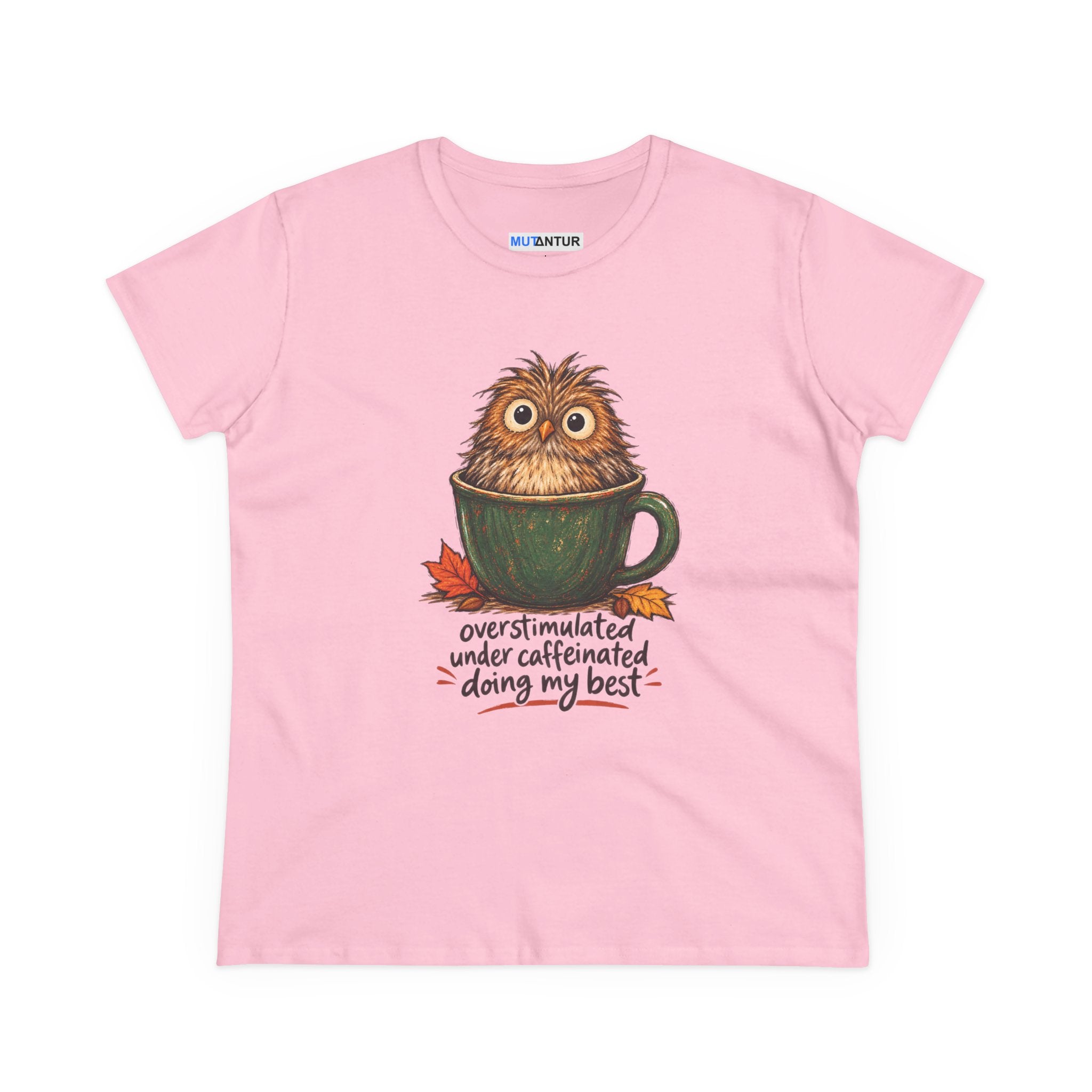 A light pink short-sleeve t-shirt with a graphic of a cute, fluffy brown owl sitting inside a green coffee mug, with the text 'overstimulated under caffeinated doing my best' written below. 