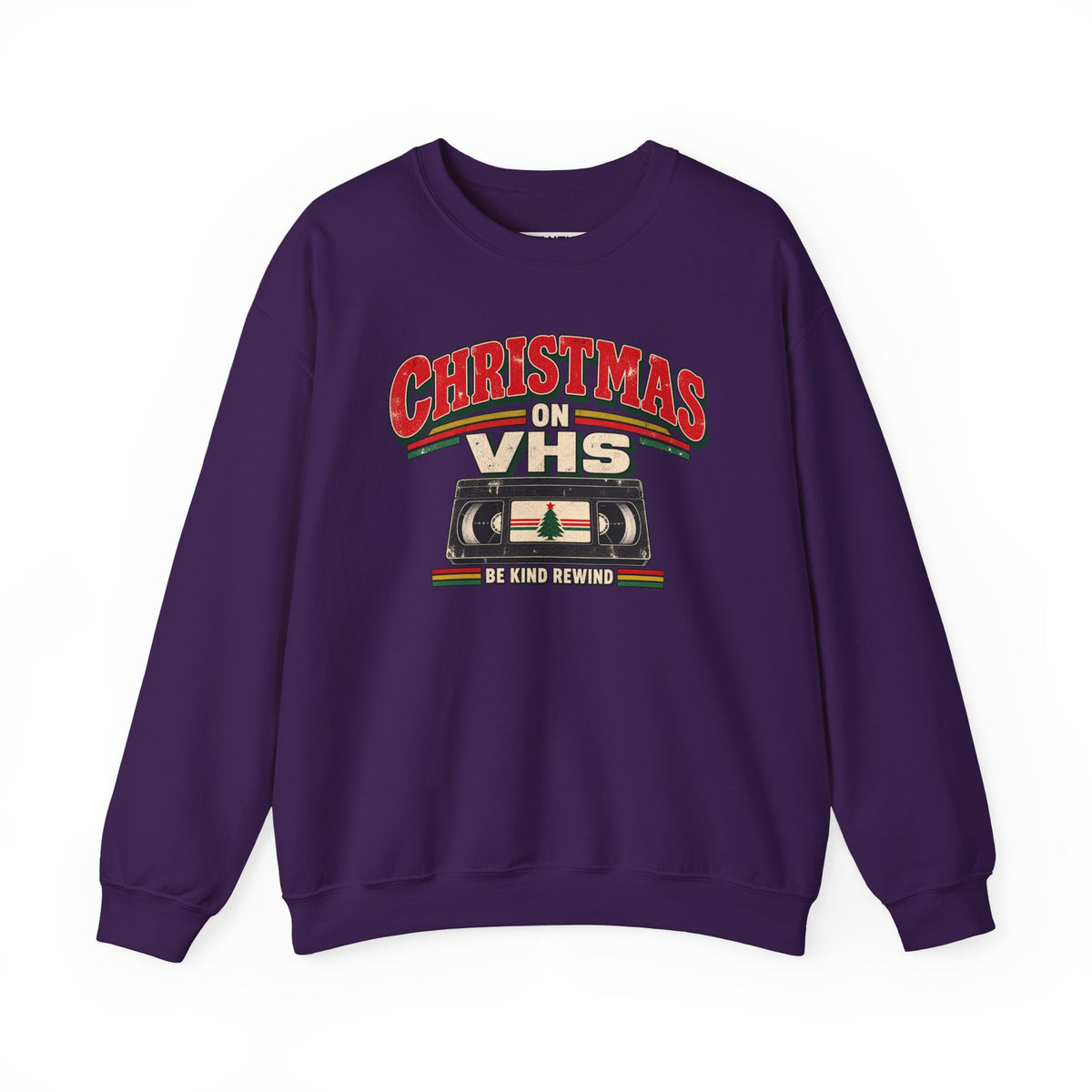A purple crewneck sweatshirt featuring a retro Christmas graphic on the chest that reads 'CHRISTMAS ON VHS' in red and cream lettering above a cassette tape illustration, with 'BE KIND REWIND' underneath.