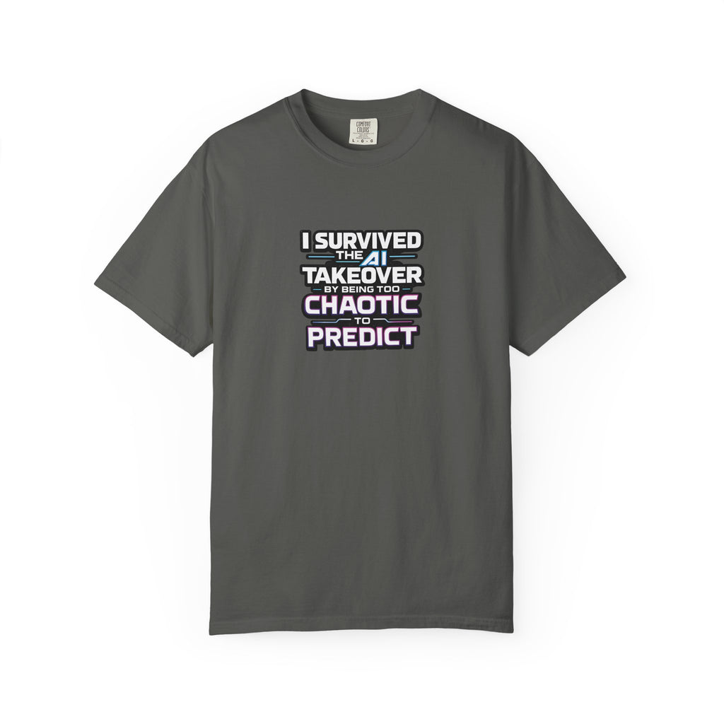 A grey short-sleeve t-shirt with a graphic text print on the chest that reads 'I SURVIVED THE AI TAKEOVER BY BEING TOO CHAOTIC TO PREDICT'. The shirt is displayed flat against a clean white background.